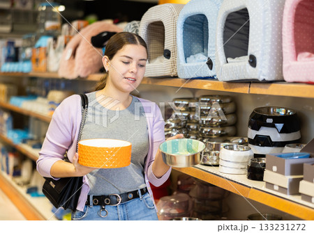 Young woman choosing bowl for puppy in pet supplies store 133231272