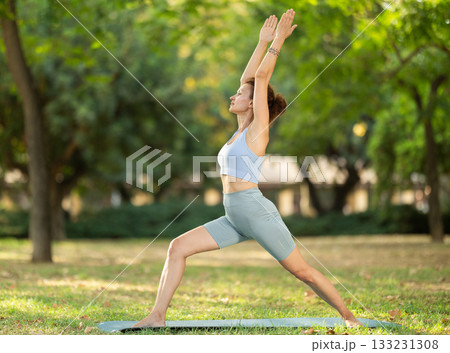 Woman practicing yoga in garden, performing Anjaneyasana, or Crescent Moon Pose Woman practicing yoga in garden, performing Anjaneyasana, or Crescent Moon Pose 133231308