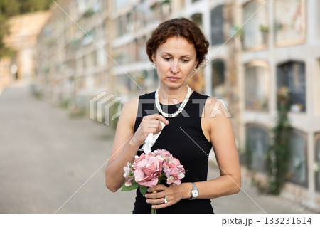 Woman brought flowers to the cemetery and cries over the death of beloved relative Woman brought flowers to the cemetery and cries over the death of beloved relative 133231614