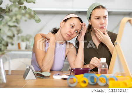 Two women looking at themselves in mirror 133232124