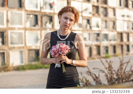 Woman brought flowers to the cemetery and cries over the death of beloved relative Woman brought flowers to the cemetery and cries over the death of beloved relative 133232339