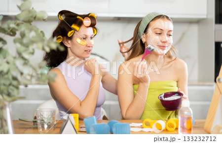 Woman applying facial mask during home spa day with bestie 133232712