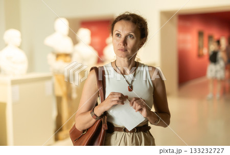 Woman looks at museum sculptures with brochure Woman looks at museum sculptures with brochure 133232727
