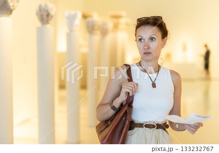 Woman looking at antique museum exhibit with brochure 133232767
