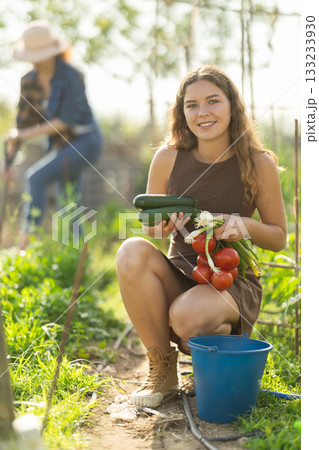Young woman with vegetable harvest in cottage garden Young woman with vegetable harvest in cottage garden 133233930
