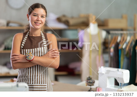 young dressmaker stands near the table and smiles 133233937