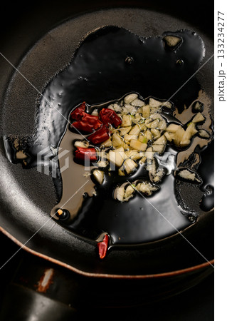 ニンニクと唐辛子をオリーブオイルで炒める様子 133234277