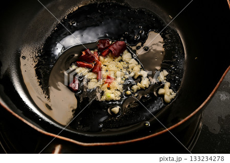 ニンニクと唐辛子をオリーブオイルで炒める様子 133234278
