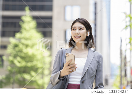イヤホンをつけスマートフォンを持った30代のビジネスウーマン 133234284