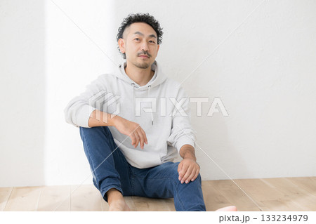 床に座るカジュアルな服装の髭の男性の全身 133234979