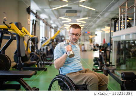 Disabled male athlete working out with dumbbell, doing weight lifting exercise for arm strength. 133235387