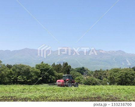 那須岳を背にした農地とトラクター 133238700