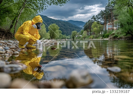 Scientist in protective suit collecting water sample from river for pollution analysis 133239187