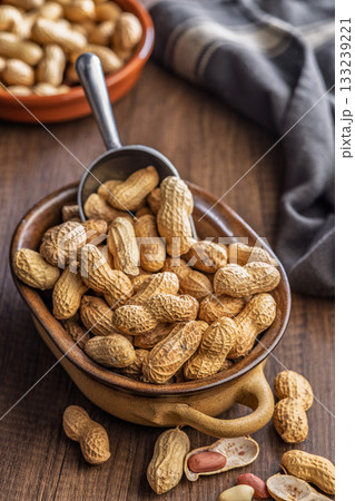 Peanuts in shell. Groundnuts  in bowl on wooden table. 133239221