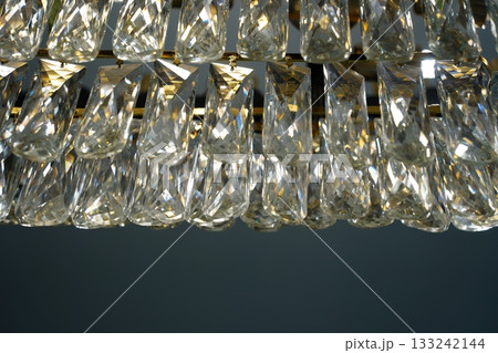 Close-up view of sparkling crystal elements and prisms on a luxurious chandelier, providing an elegant background or texture. Close-up view of sparkling crystal elements and prisms on a luxurious chandelier, providing an elegant background or texture. 133242144