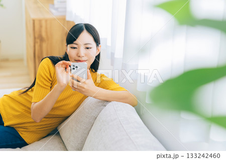 ソファでスマホを見る若い女性 ソファでスマホを見る若い女性 133242460
