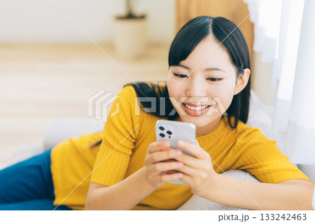 ソファでスマホを見る若い女性 ソファでスマホを見る若い女性 133242463