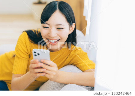 ソファでスマホを見る若い女性 ソファでスマホを見る若い女性 133242464