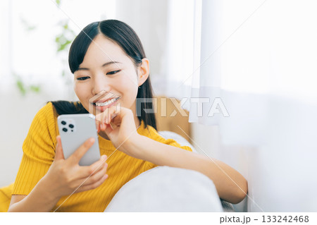 ソファでスマホを見る若い女性 133242468