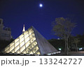 都会の風景ライトアップされたピラミッド型の建造物と月 133242727