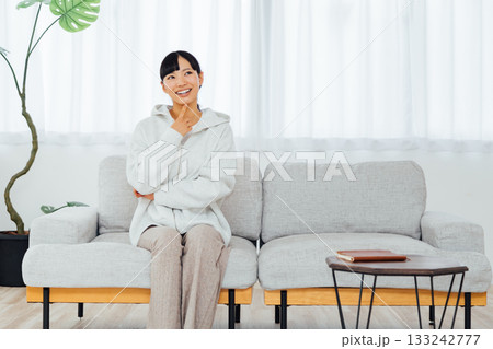 部屋でくつろぎながら楽しみな予定に思いをはせる女性 133242777