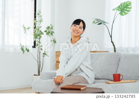 部屋でくつろぎながら楽しみな予定に思いをはせる女性 部屋でくつろぎながら楽しみな予定に思いをはせる女性 133242785