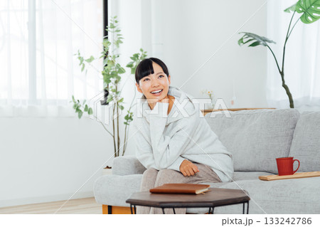 部屋でくつろぎながら楽しみな予定に思いをはせる女性 133242786