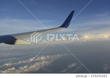 旅客機の翼に当たる夕日と雲海 133243201