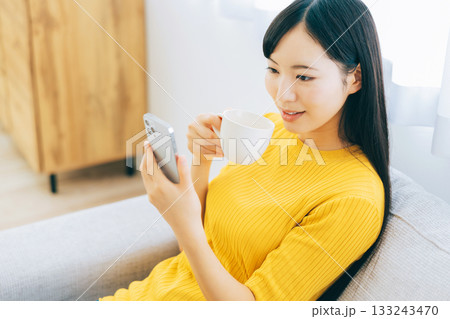 ソファでスマホを見る若い女性 ソファでスマホを見る若い女性 133243470