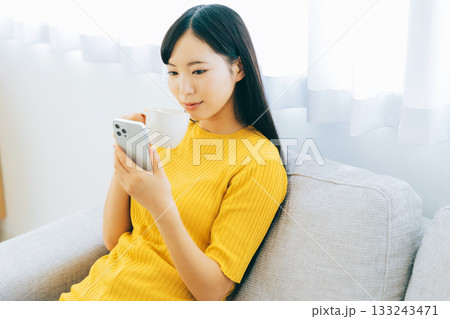 ソファでスマホを見る若い女性 ソファでスマホを見る若い女性 133243471