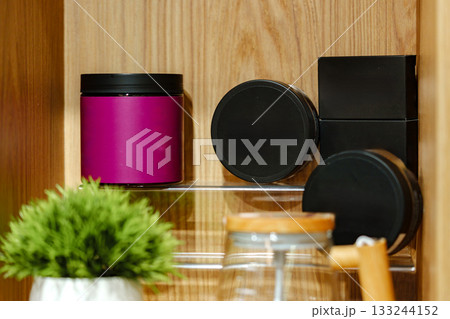 Colorful jars and containers arranged neatly on a wooden shelf in a cozy setting 133244152