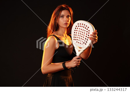 Female athlete poses confidently with a racket in a dramatic lighting setup 133244317