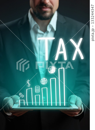 Businessman holding tablet displaying tax-related graphs and symbols in dark room Businessman holding tablet displaying tax-related graphs and symbols in dark room 133244347