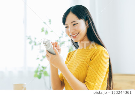 リビングでスマホを見る若い女性 133244361