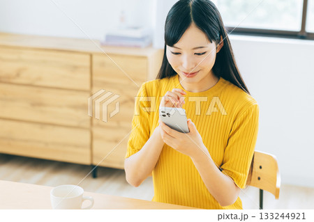 リビングでスマホを見る若い女性 133244921