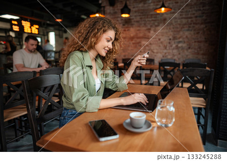 Young Woman Making Online Payment with Credit Card in Cafe Young Woman Making Online Payment with Credit Card in Cafe 133245288