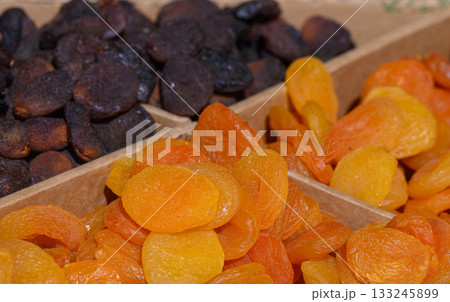 Dried fruit selection displays vibrant colors and rich textures of sweet apricots and dark prunes at a bustling market stand 133245899