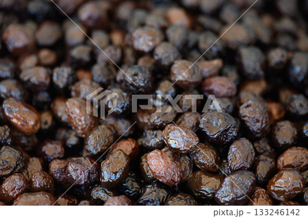 Dark and glossy dried fruits create a rich tapestry of textures in a rustic market setting 133246142