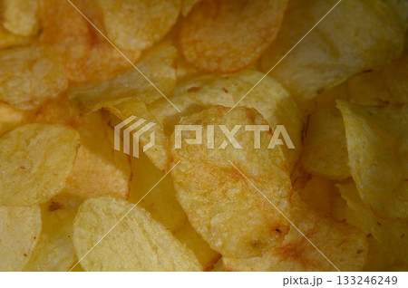 Crunchy golden potato chips scattered in a bowl create a tempting snack experience at any gathering 133246249
