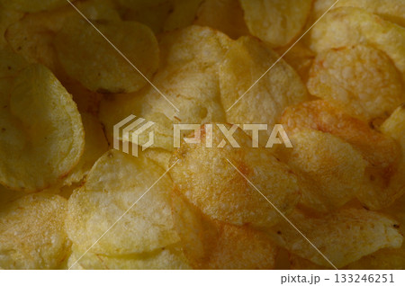 Crunchy golden potato chips piled high in a bowl, perfect for snacking at any casual gathering or party 133246251