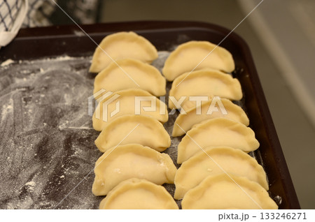 Homemade dumplings arranged meticulously on a wooden tray ready for cooking 133246271