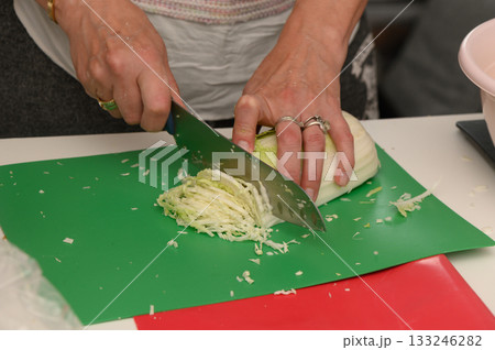 Mastering the art of chopping cabbage in a vibrant kitchen during a culinary workshop Mastering the art of chopping cabbage in a vibrant kitchen during a culinary workshop 133246282