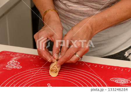 Crafting delicate dumplings in a cozy kitchen filled with warmth and flour 133246284