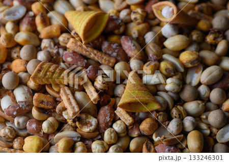 Colorful mix of nuts and snacks spread out on a wooden surface in a sunny kitchen Colorful mix of nuts and snacks spread out on a wooden surface in a sunny kitchen 133246301