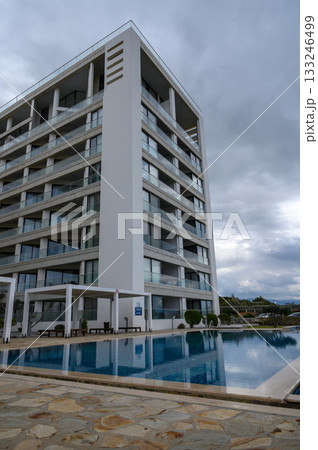 Modern architectural design enhances relaxation at a luxurious hotel by the tranquil pool on a cloudy afternoon Modern architectural design enhances relaxation at a luxurious hotel by the tranquil pool on a cloudy afternoon 133246499