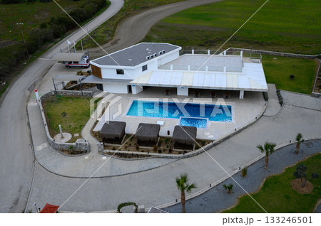 Luxury villa with a sparkling pool surrounded by lush greenery in a serene landscape at dusk 133246501