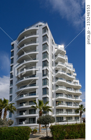 Modern architectural marvel stands tall against the bright blue sky with lush greenery below Modern architectural marvel stands tall against the bright blue sky with lush greenery below 133246553