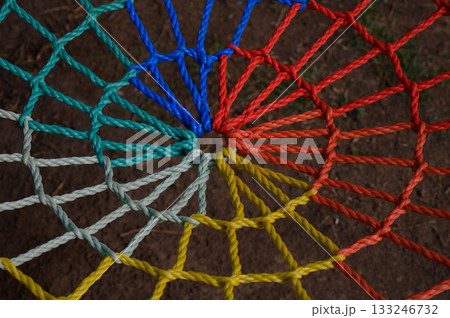 Colorful spiral design of intertwined ropes creates a mesmerizing pattern on the ground 133246732