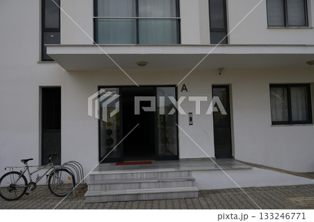 Entrance of a modern building with bicycle parked nearby on a quiet street during overcast weather Entrance of a modern building with bicycle parked nearby on a quiet street during overcast weather 133246771