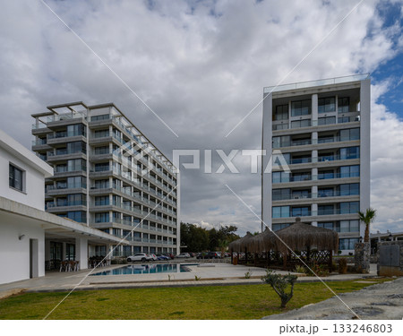 Modern resort buildings under a cloudy sky with a serene poolside view in a tranquil vacation destination Modern resort buildings under a cloudy sky with a serene poolside view in a tranquil vacation destination 133246803